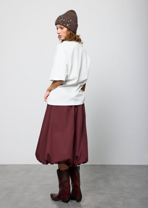Bordowa damska spódnica midi o fasonie balonowym, z szerokim pasem w talii i marszczeniem u góry, wykonana z miękkiej, lejącej tkaniny; dół zaokrąglony z podwinięciem, styl nowoczesny i elegancki.