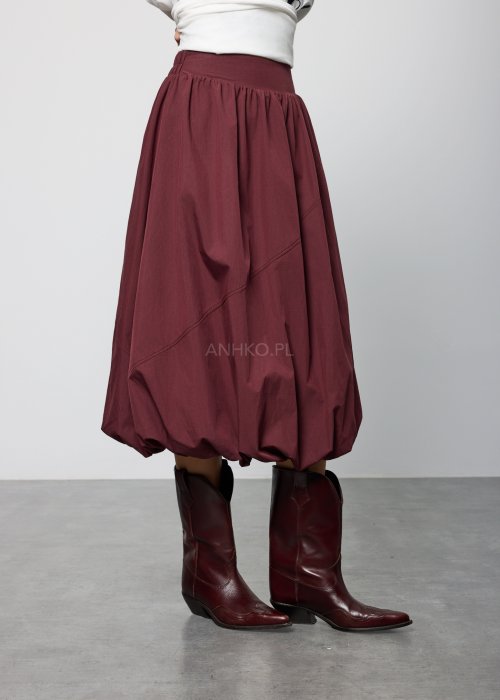 Bordowa damska spódnica midi o fasonie balonowym, z szerokim pasem w talii i marszczeniem u góry, wykonana z miękkiej, lejącej tkaniny; dół zaokrąglony z podwinięciem, styl nowoczesny i elegancki.