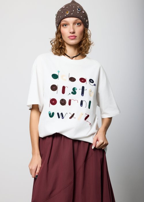 Biały damski T-shirt o luźnym kroju, z krótkim rękawem i okrągłym dekoltem, ozdobiony kolorowym haftem i aplikacjami w formie liter na przodzie; styl casual, artystyczny