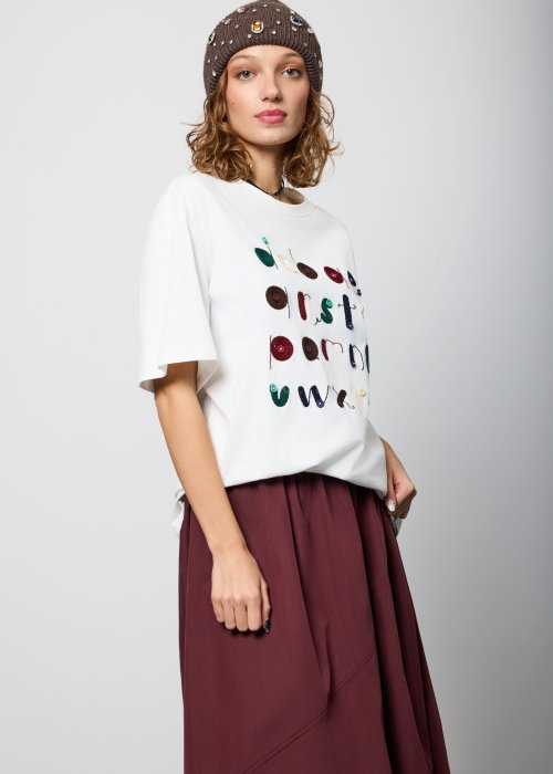Biały damski T-shirt o luźnym kroju, z krótkim rękawem i okrągłym dekoltem, ozdobiony kolorowym haftem i aplikacjami w formie liter na przodzie; styl casual, artystyczny