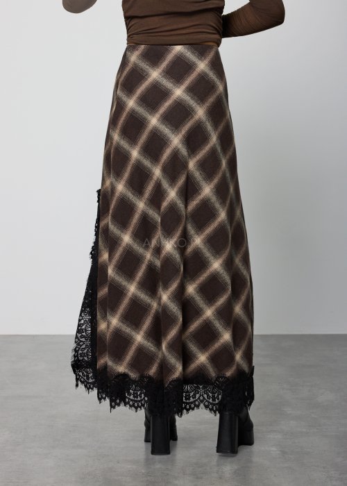 Długa damska spódnica w brązową kratę, o prostym, lekko rozszerzanym kroju; wykończona u dołu czarną koronką, noszona z czarnymi botkami na platformie.