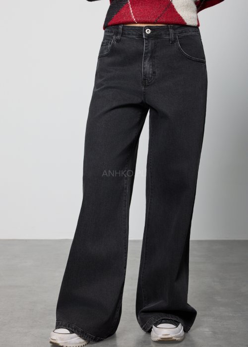 Czarne damskie jeansy z prostą, lekko rozszerzaną nogawką, klasyczny krój z pięcioma kieszeniami i zapięciem na guzik, noszone z białymi sneakersami.