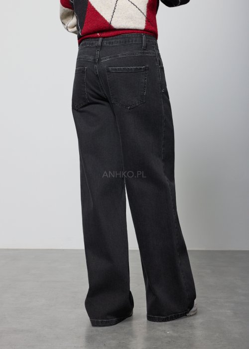 Czarne damskie jeansy z prostą, lekko rozszerzaną nogawką, klasyczny krój z pięcioma kieszeniami i zapięciem na guzik, noszone z białymi sneakersami.