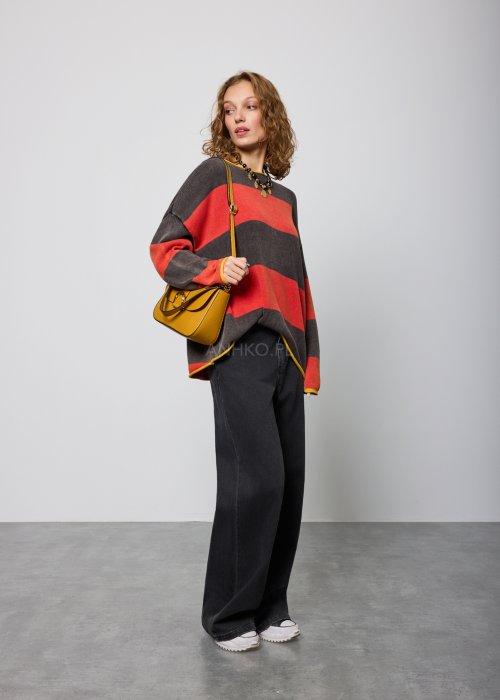 Czarne damskie jeansy z prostą, lekko rozszerzaną nogawką, klasyczny krój z pięcioma kieszeniami i zapięciem na guzik, noszone z białymi sneakersami.