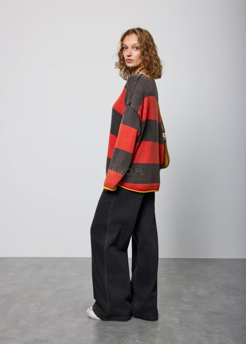 Czarne damskie jeansy z prostą, lekko rozszerzaną nogawką, klasyczny krój z pięcioma kieszeniami i zapięciem na guzik, noszone z białymi sneakersami.