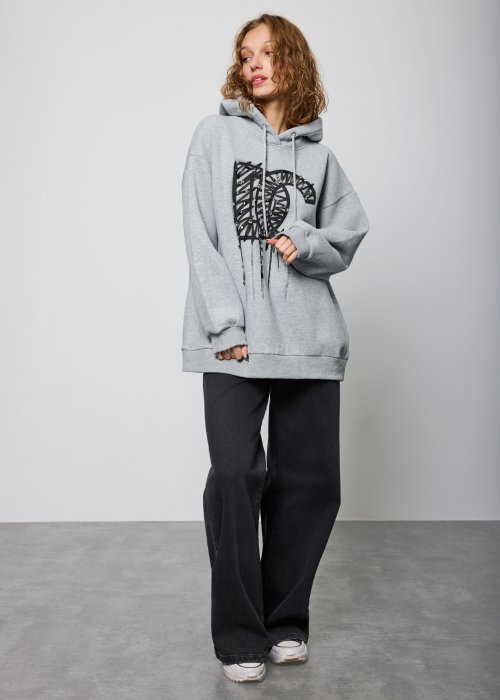 Czarne damskie jeansy z prostą, lekko rozszerzaną nogawką, klasyczny krój z pięcioma kieszeniami i zapięciem na guzik, noszone z białymi sneakersami.