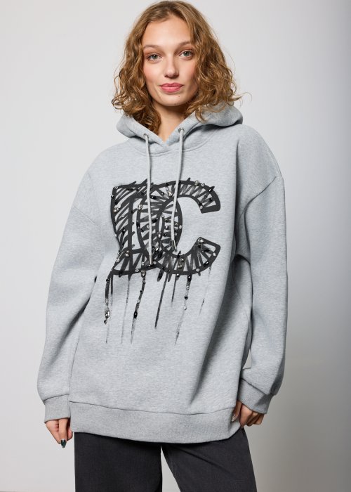 Damska szara bluza z kapturem o luźnym kroju, z dużym czarnym nadrukiem litery „C” ozdobionym aplikacjami i efektem spływającej farby