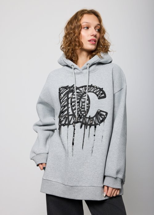 Damska szara bluza z kapturem o luźnym kroju, z dużym czarnym nadrukiem litery „C” ozdobionym aplikacjami i efektem spływającej farby