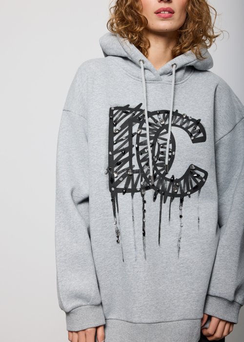 Damska szara bluza z kapturem o luźnym kroju, z dużym czarnym nadrukiem litery „C” ozdobionym aplikacjami i efektem spływającej farby