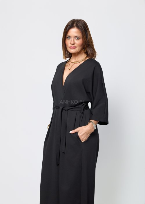 Czarny damski kombinezon o eleganckim, minimalistycznym kroju. Model z głębokim dekoltem w kształcie litery V, rękawami 3/4 i paskiem do wiązania w talii
