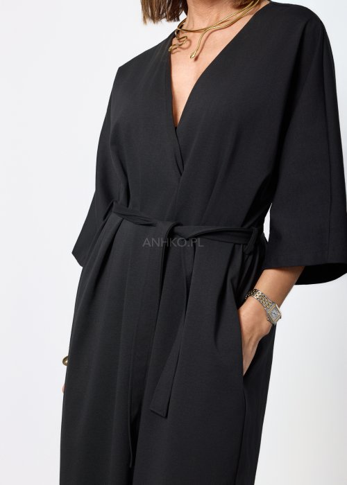 Czarny damski kombinezon o eleganckim, minimalistycznym kroju. Model z głębokim dekoltem w kształcie litery V, rękawami 3/4 i paskiem do wiązania w talii