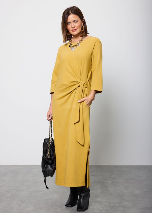 Damska sukienka midi w kolorze musztardowym, o prostym kroju z długimi rękawami i ozdobnym wiązaniem w talii po boku.