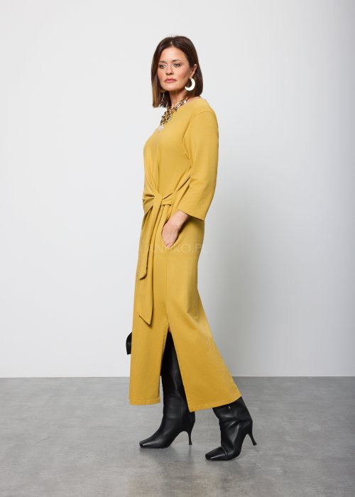 Damska sukienka midi w kolorze musztardowym, o prostym kroju z długimi rękawami i ozdobnym wiązaniem w talii po boku.