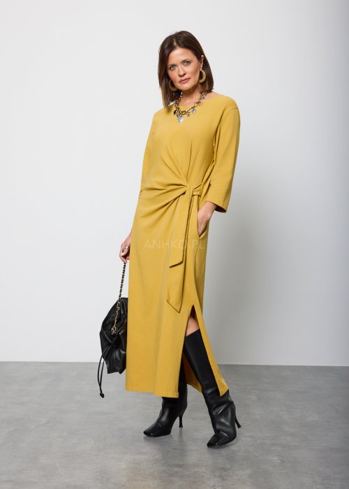 Damska sukienka midi w kolorze musztardowym, o prostym kroju z długimi rękawami i ozdobnym wiązaniem w talii po boku.