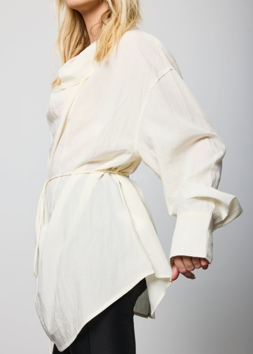 Kremowa damska bluzka o luźnym kroju, z długimi rękawami i miękko drapowanym dekoltem, przewiązywana cienkim paskiem w talii