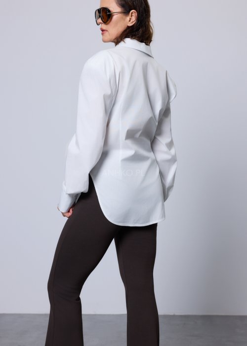 Biała koszula damska o klasycznym kroju z kołnierzykiem, zapinana na guziki, z długimi rękawami zakończonymi mankietami; delikatnie taliowana