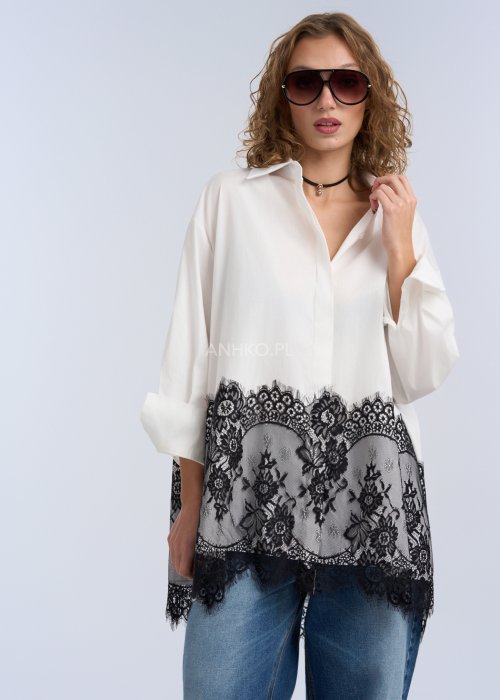 Biała koszula oversize z czarną, dekoracyjną koronką u dołu, długi rękaw i klasyczne zapięcie na guziki, stylizacja z jeansami.