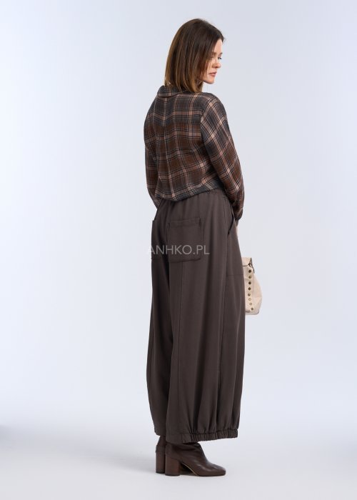 luźne, szerokie spodnie o długości do kostek, utrzymane w ciemnym, czekoladowo-brązowym kolorze. Mają elastyczną talię, która zapewnia wygodę i miękkie dopasowanie w pasie.
