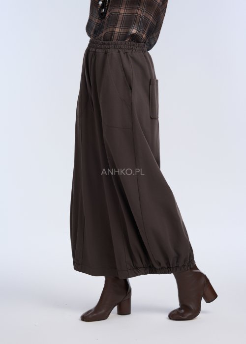 luźne, szerokie spodnie o długości do kostek, utrzymane w ciemnym, czekoladowo-brązowym kolorze. Mają elastyczną talię, która zapewnia wygodę i miękkie dopasowanie w pasie.