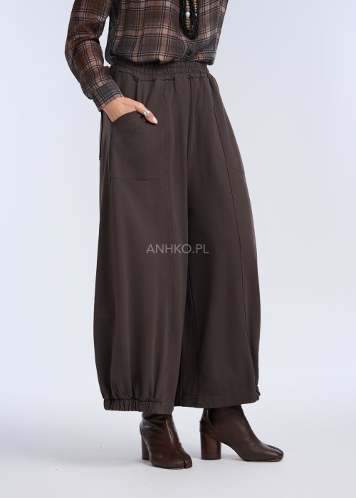 luźne, szerokie spodnie o długości do kostek, utrzymane w ciemnym, czekoladowo-brązowym kolorze. Mają elastyczną talię, która zapewnia wygodę i miękkie dopasowanie w pasie.