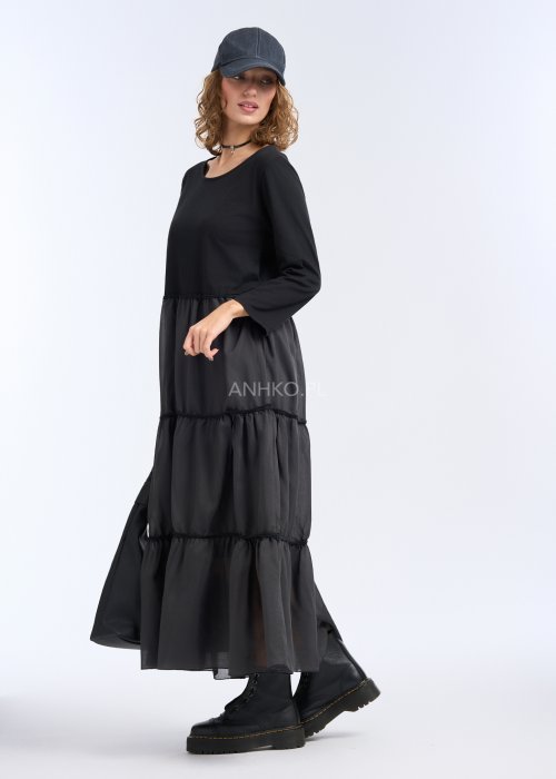 To długa, czarna sukienka o luźnym fasonie, sięgająca do kostek. Góra jest prosta i gładka, z okrągłym dekoltem oraz rękawami o długości 3/4
