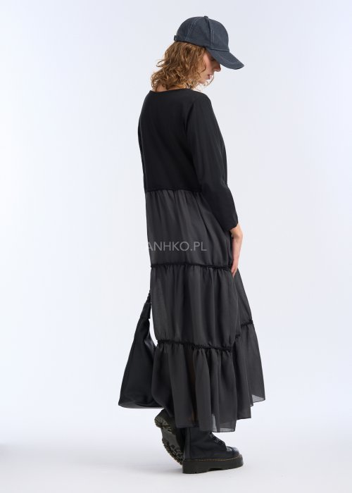 To długa, czarna sukienka o luźnym fasonie, sięgająca do kostek. Góra jest prosta i gładka, z okrągłym dekoltem oraz rękawami o długości 3/4