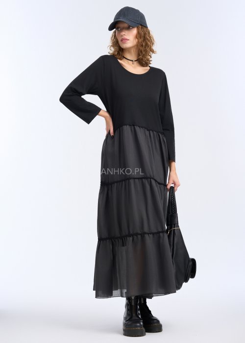 To długa, czarna sukienka o luźnym fasonie, sięgająca do kostek. Góra jest prosta i gładka, z okrągłym dekoltem oraz rękawami o długości 3/4