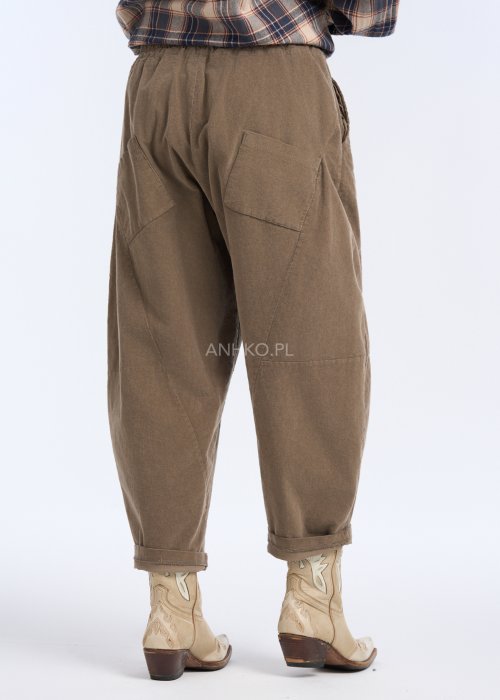 Są to luźne spodnie w kolorze brązowym, o komfortowym, swobodnym fasonie. Mają elastyczną talię z troczkiem do regulacji