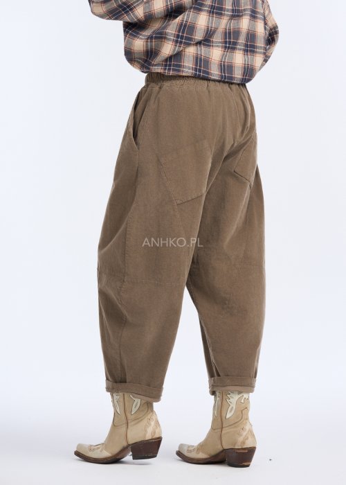 Są to luźne spodnie w kolorze brązowym, o komfortowym, swobodnym fasonie. Mają elastyczną talię z troczkiem do regulacji