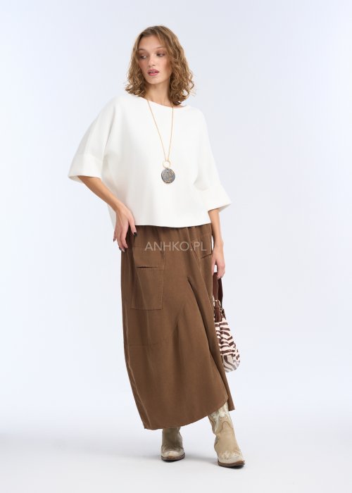 To biała, luźna bluzka o prostym, lekko oversize’owym kroju. Ma szerokie rękawy do łokcia, delikatnie rozszerzane, co nadaje jej lekkości i elegancji.