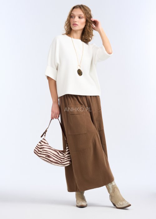 To biała, luźna bluzka o prostym, lekko oversize’owym kroju. Ma szerokie rękawy do łokcia, delikatnie rozszerzane, co nadaje jej lekkości i elegancji.