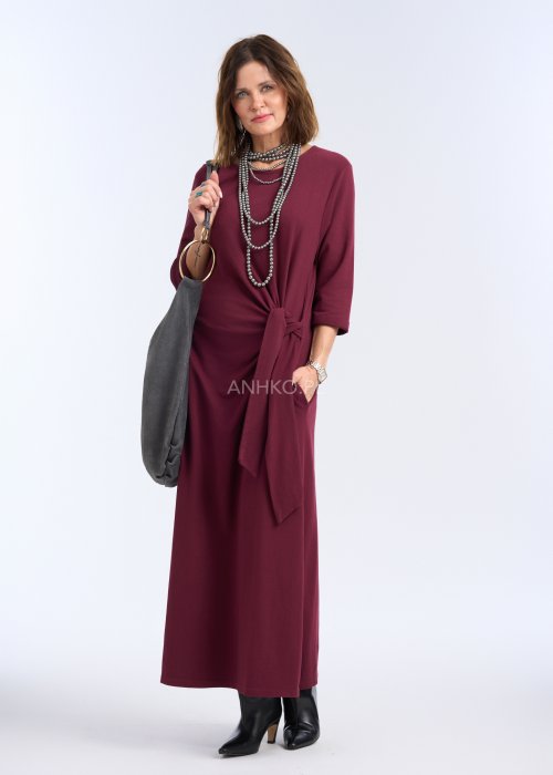 To sukienka maxi w głębokim, bordowym kolorze, o prostym, eleganckim kroju. Ma rękawy o długości 3/4 oraz okrągły dekolt