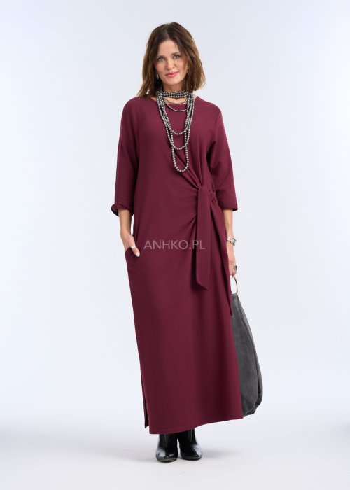 To sukienka maxi w głębokim, bordowym kolorze, o prostym, eleganckim kroju. Ma rękawy o długości 3/4 oraz okrągły dekolt