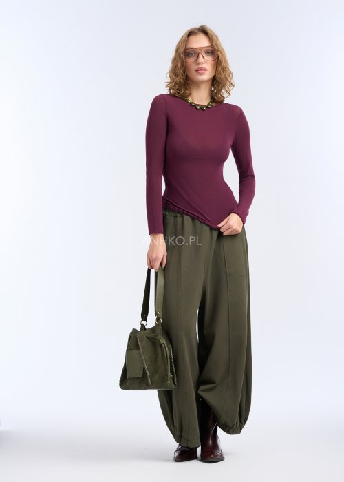 Bluzka ma prosty, przylegający fason, długi rękaw oraz gładką powierzchnię bez zdobień, co podkreśla sylwetkę i nadaje całości elegancki, minimalistyczny charakter.