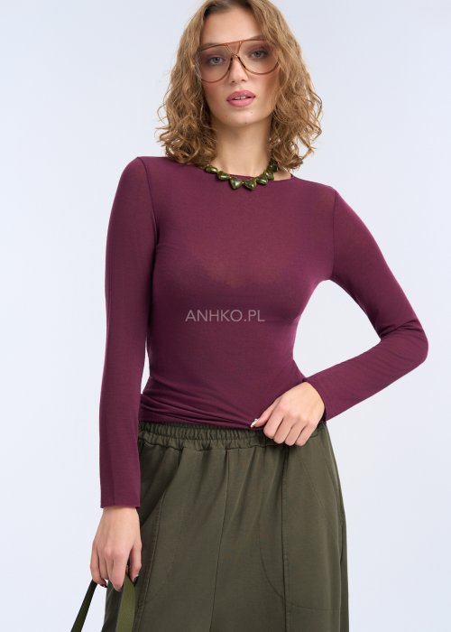 Bluzka ma prosty, przylegający fason, długi rękaw oraz gładką powierzchnię bez zdobień, co podkreśla sylwetkę i nadaje całości elegancki, minimalistyczny charakter.