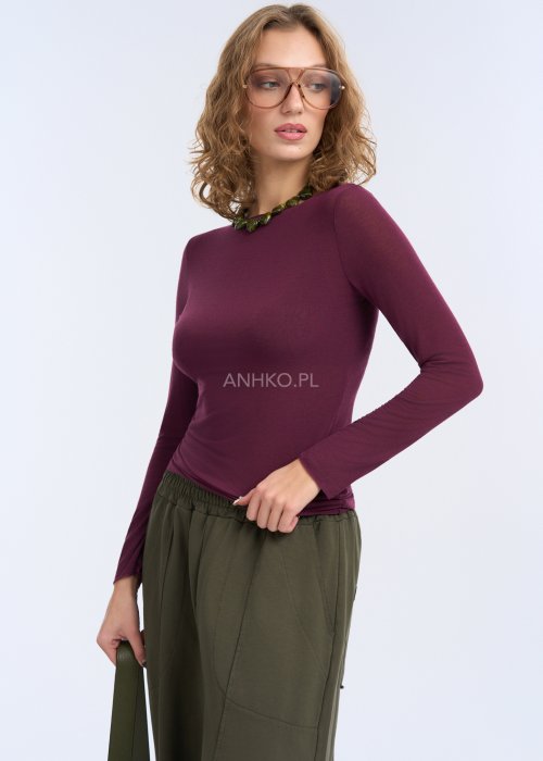 Bluzka ma prosty, przylegający fason, długi rękaw oraz gładką powierzchnię bez zdobień, co podkreśla sylwetkę i nadaje całości elegancki, minimalistyczny charakter.