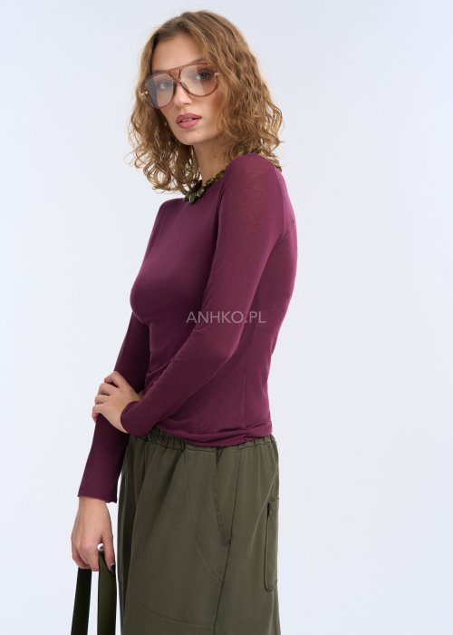 Bluzka ma prosty, przylegający fason, długi rękaw oraz gładką powierzchnię bez zdobień, co podkreśla sylwetkę i nadaje całości elegancki, minimalistyczny charakter.
