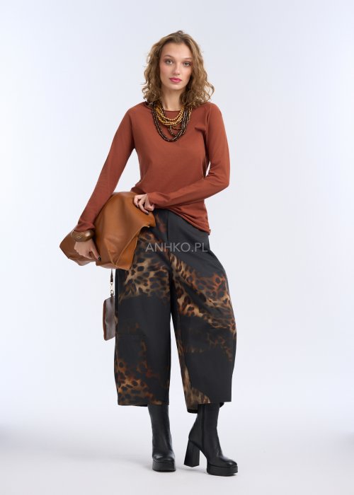 Szerokie spodnie damskie o długości 7/8, czarne z wyraźnym brązowym wzorem zwierzęcym (panterka), proste nogawki, gładki pas w talii; zestawione z czarnymi botkami na platformie