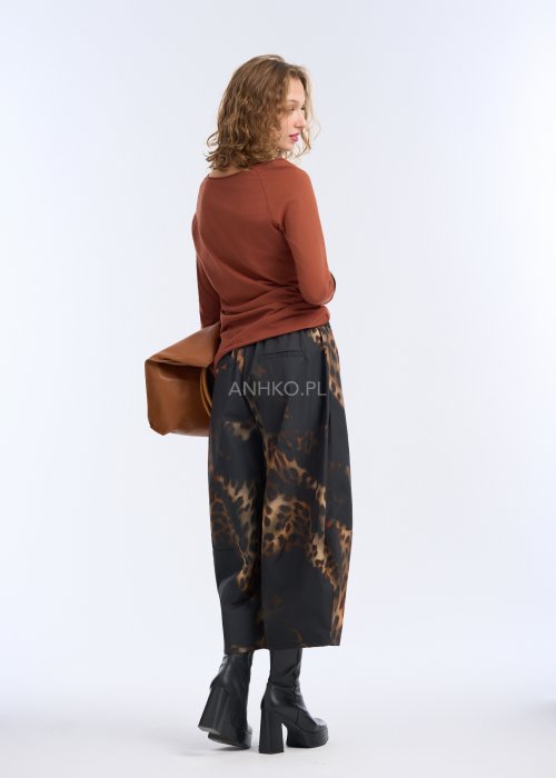 Szerokie spodnie damskie o długości 7/8, czarne z wyraźnym brązowym wzorem zwierzęcym (panterka), proste nogawki, gładki pas w talii; zestawione z czarnymi botkami na platformie