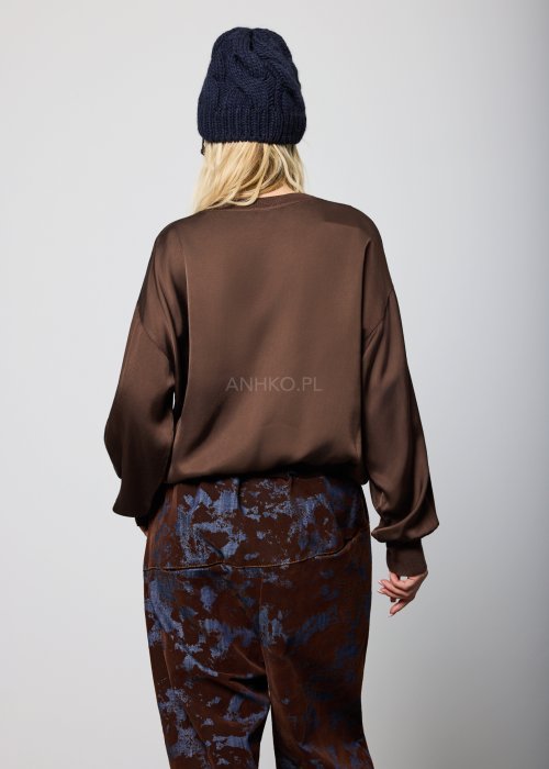 Luźna bluzka damska w kolorze czekoladowego brązu, z długimi rękawami zakończonymi ściągaczem oraz elastycznym dołem, noszona swobodnie na spodniach