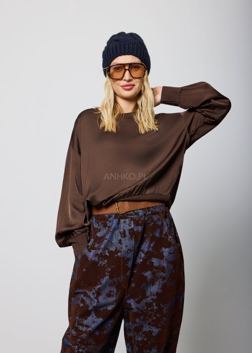 Luźna bluzka damska w kolorze czekoladowego brązu, z długimi rękawami zakończonymi ściągaczem oraz elastycznym dołem, noszona swobodnie na spodniach