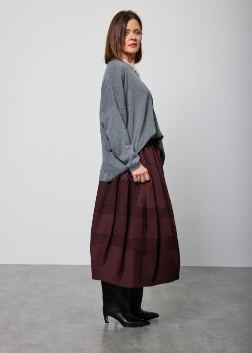 Luźny, szary sweter z długim rękawem i dekoltem w serek, noszony do burgundowej spódnicy