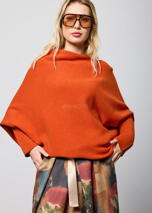 Ceglany sweter damski oversize o nietoperzowym kroju z asymetrycznym dołem, stylizacja miejska z dodatkami.