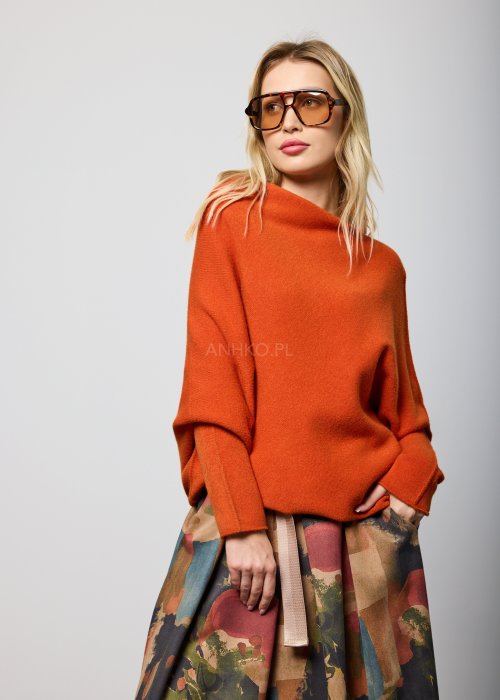 Ceglany sweter damski oversize o nietoperzowym kroju z asymetrycznym dołem, stylizacja miejska z dodatkami.