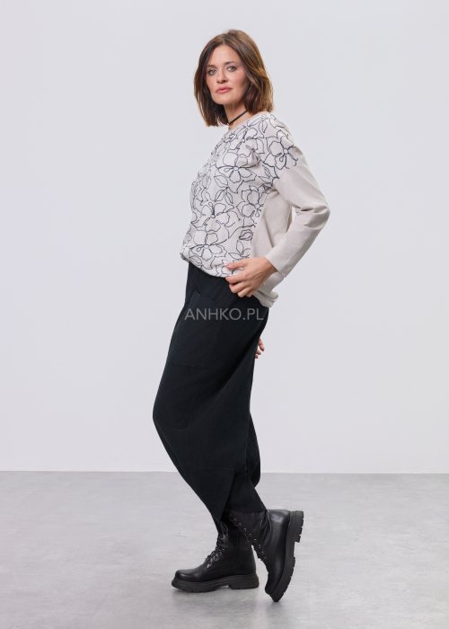 Jasna bluzka damska z długim rękawem, wykonana z lekkiej tkaniny, z dekoracyjnym haftem w kontrastowy kwiatowy wzór na przodzie; prosty, swobodny krój, okrągły dekolt, stylizacja na jasnym tle