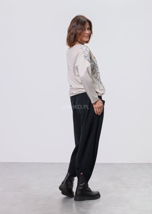 Jasna bluzka damska z długim rękawem, wykonana z lekkiej tkaniny, z dekoracyjnym haftem w kontrastowy kwiatowy wzór na przodzie; prosty, swobodny krój, okrągły dekolt, stylizacja na jasnym tle