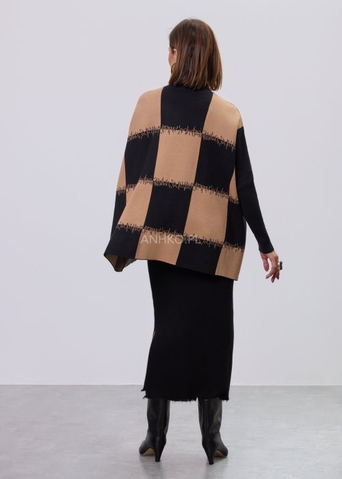 Beżowo-czarna damska tunika z dzianiny o luźnym kroju, z geometrycznym wzorem pasów i półgolfem, długie rękawy, prezentowana na modelce na jasnym tle