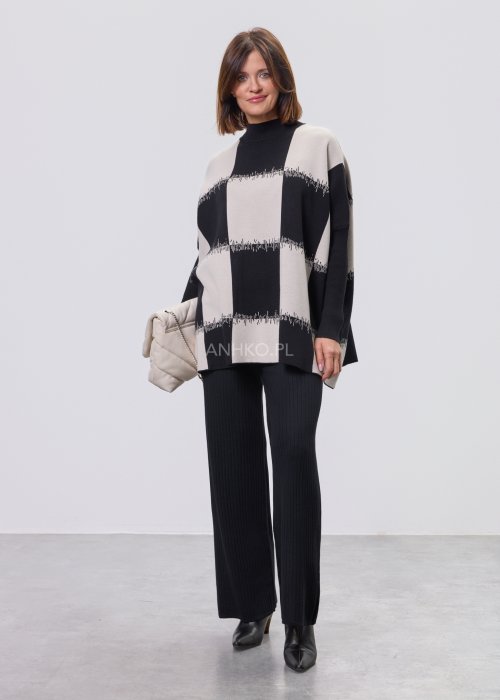 Czarno-ecru damska tunika dzianinowa o luźnym kroju, z półgolfem i długimi rękawami, w geometryczny wzór pasów z delikatnym motywem graficznym, prezentowana na modelce na jasnym tle