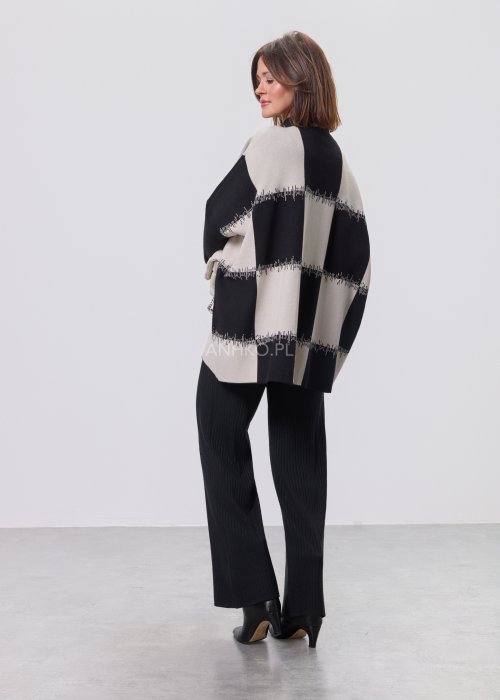 Czarno-ecru damska tunika dzianinowa o luźnym kroju, z półgolfem i długimi rękawami, w geometryczny wzór pasów z delikatnym motywem graficznym, prezentowana na modelce na jasnym tle