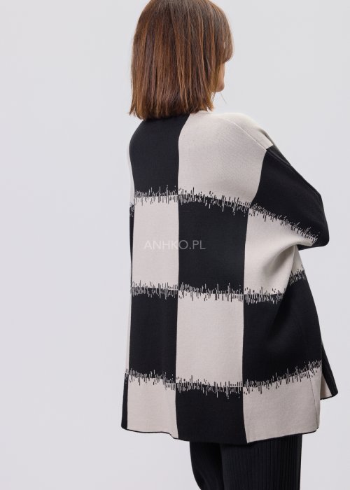 Czarno-ecru damska tunika dzianinowa o luźnym kroju, z półgolfem i długimi rękawami, w geometryczny wzór pasów z delikatnym motywem graficznym, prezentowana na modelce na jasnym tle